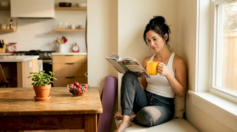 Woman reading health book in bright kitchen
