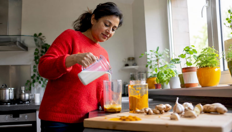 Woman preparing turmeric golden milk in kitchen