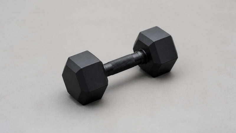 Sleek black dumbbells on a minimalist grey background representing the efficiency of low-volume training